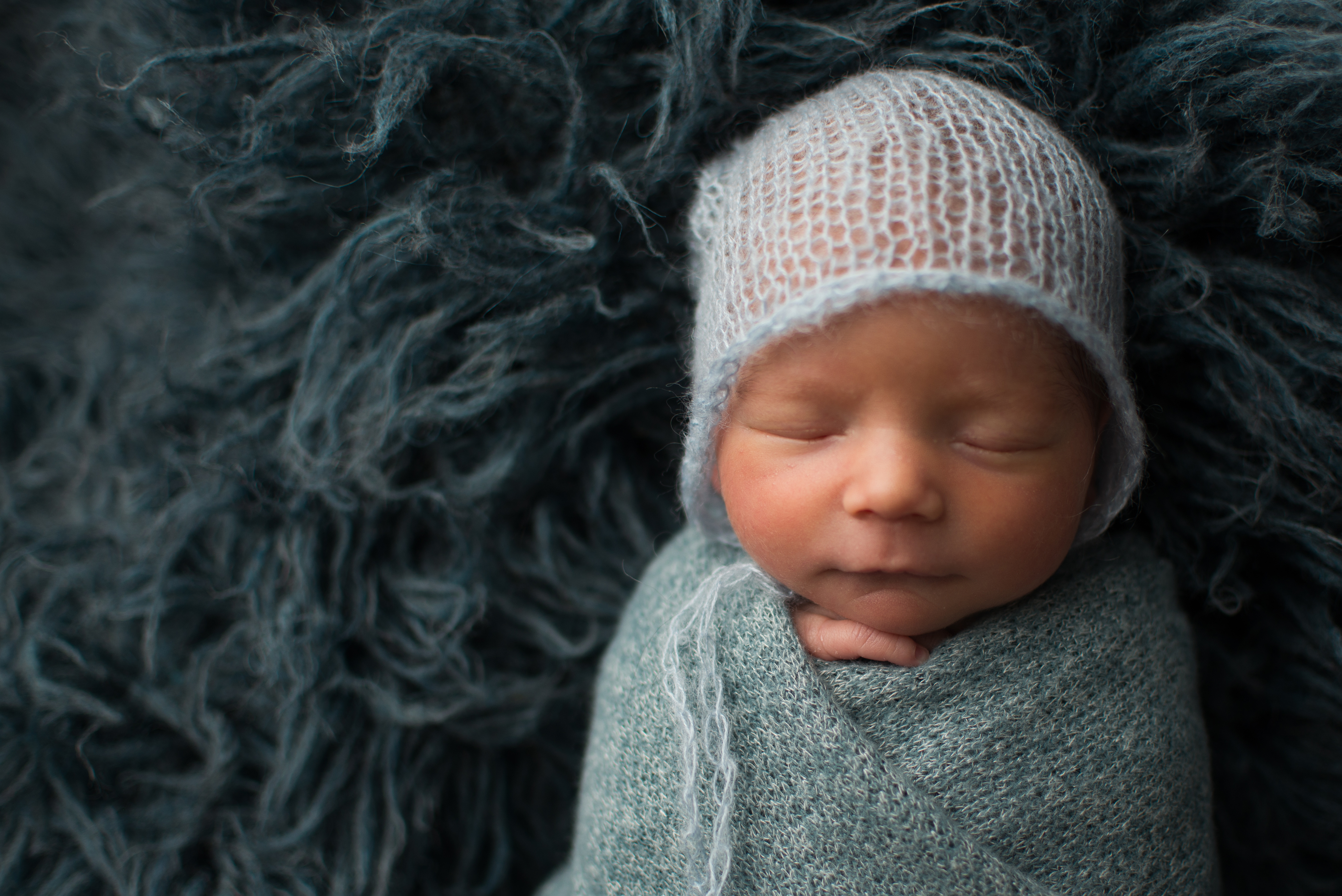 Sleeping newborn baby swaddled in a knit wrap and cap