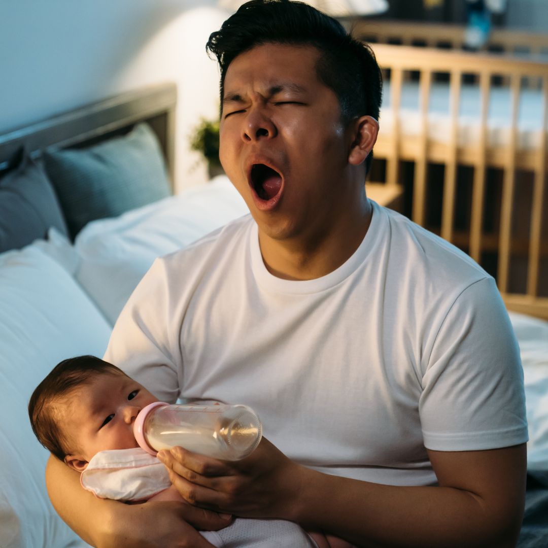 Dad feeding baby while yawning